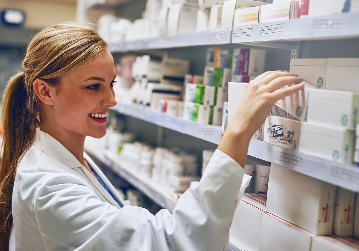 Apothekeres neemt doosje medicijnen van schap vol medicijnen